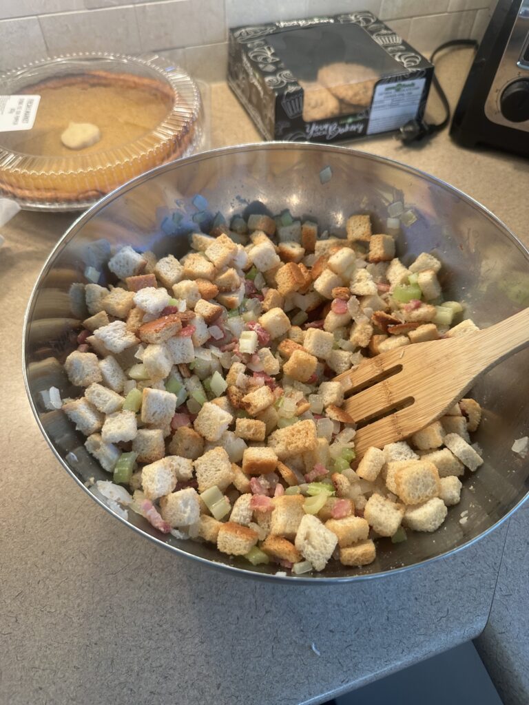 A photo of majority of the uncooked stuffing ingredients blended in a bowl. (Missing mushrooms, rosemary, thyme, and poultry seasoning)